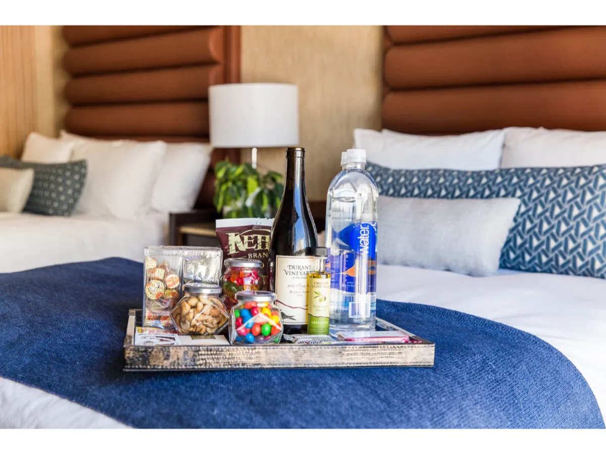 A cozy seating area with a snack tray, wine and water bottles, and decorative pillows. The atmosphere suggests a relaxing environment perfect for unwinding after a long day, with amenities easily accessible and attention to comfort.